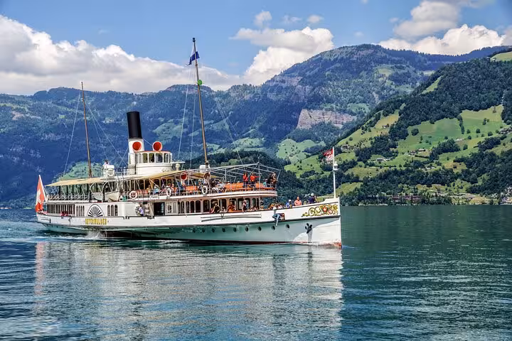 Historic paddle steamer cruises on a serene Swiss lake surrounded by majestic mountains, offering a picturesque journey.