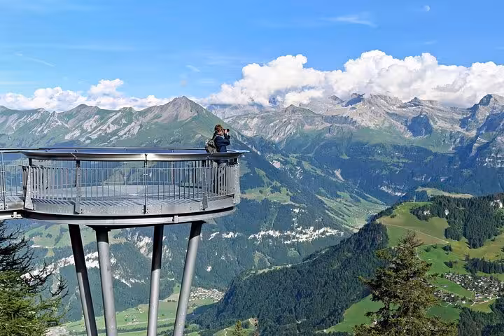 Visitor enjoys panoramic views from a Swiss mountain viewing platform on a clear day, perfect for scenic photography.
