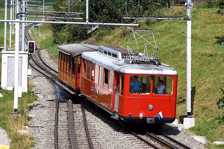 Historic Swiss red train navigating lush green meadows, offering a classic experience on a personalized train tour.