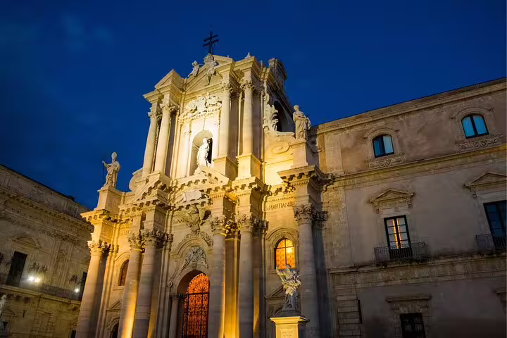 Illuminated Syracuse Cathedral facade in Ortigia at night, key stop on self-guided scavenger hunt tour