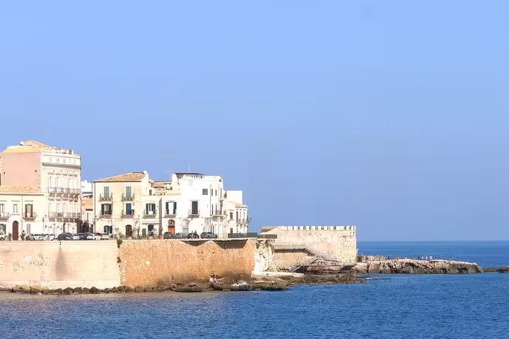 Discover the stunning coastal views of Ortigia Island in Syracuse, featuring charming historic buildings by the sea.