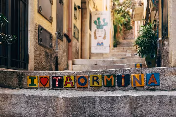 Charming alleyway in Taormina with colorful 'I Love Taormina' blocks, perfect for Messina port shore excursion.