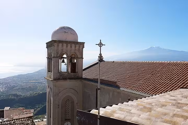 Scenic view of Taormina's historic architecture with Mount Etna in the background under a clear blue sky.