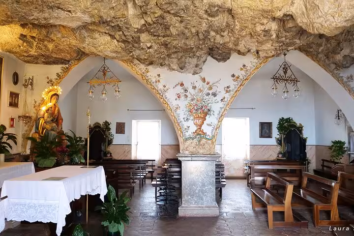 Explore a charming chapel in Taormina with rustic stone arches and floral decor, perfect for cultural tours.