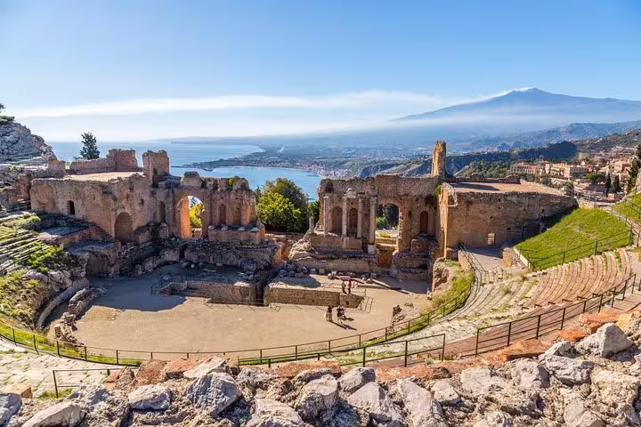 Ancient Greek theatre in Taormina with stunning views of the coastline and Mount Etna in the background.