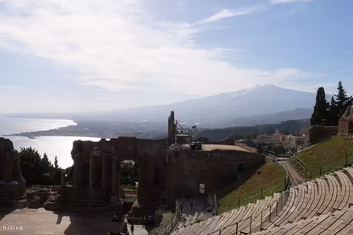 Stunning view of Taormina's ancient Greek Theatre with Mount Etna in the background, perfect for history enthusiasts.