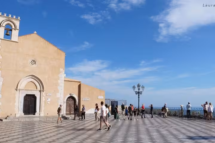 Visitors exploring Piazza IX Aprile in Taormina with scenic views, historic architecture, and a picturesque coastal backdrop.