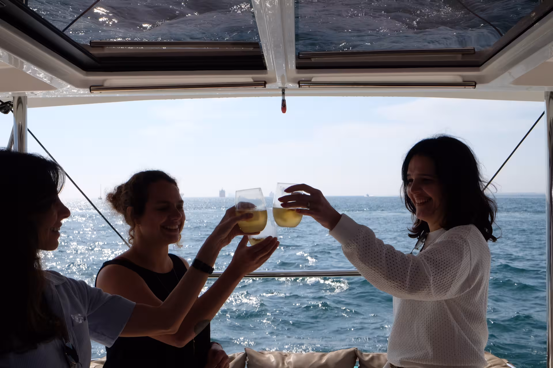 Guests toast with chilled tea on a sea-view boat, part of a relaxing tea ceremony experience at sunset