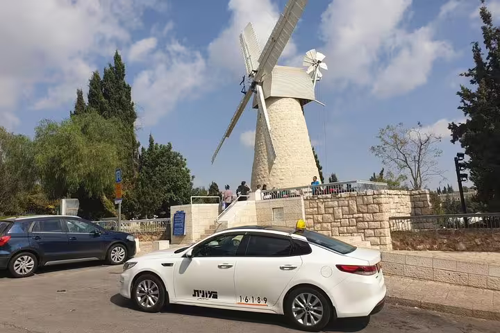 Private Tel Aviv pickup car for Dead Sea and Masada day trip, parked near Jerusalem’s historic windmill