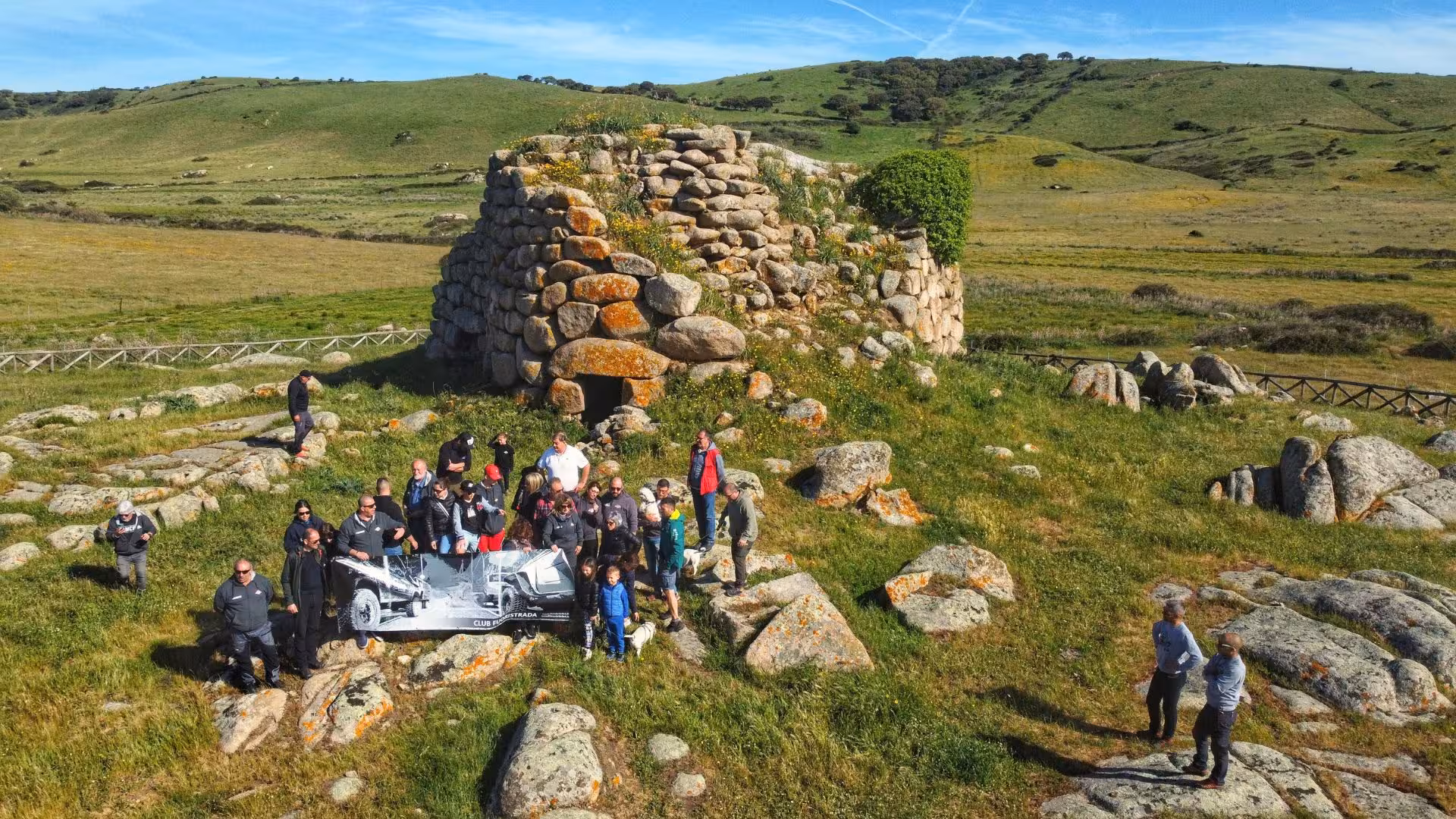 Group of tourists exploring ancient stone structure on Mount Limbara jeep tour, surrounded by lush green landscapes.
