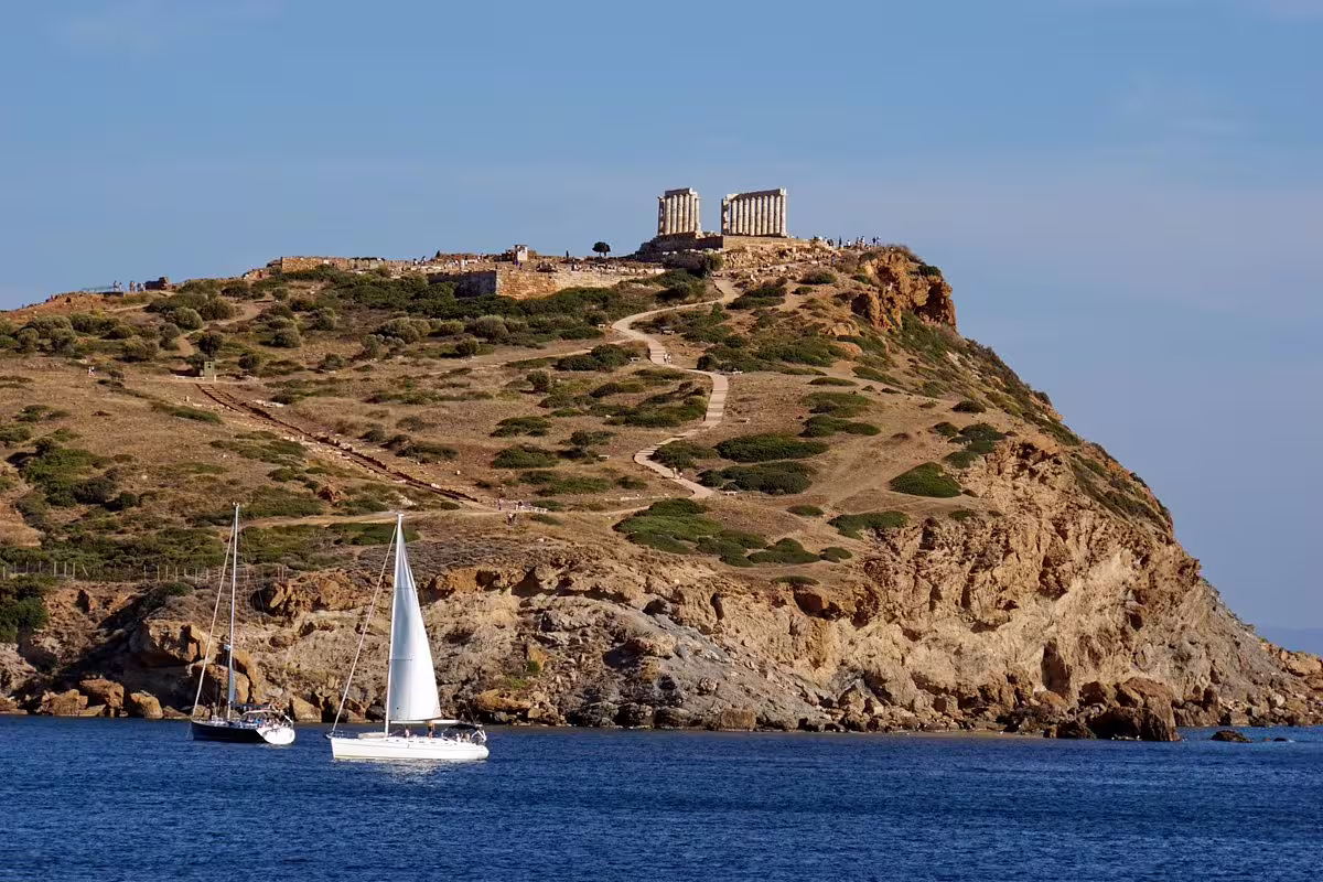 Temple of Poseidon atop Cape Sounion above the Aegean with sailboats, highlight of a private sunset tour from Athens