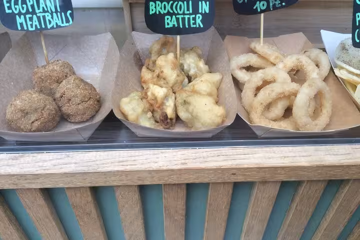 Assorted Italian street food in Testaccio Rome featuring eggplant meatballs, broccoli in batter, and fried snacks.