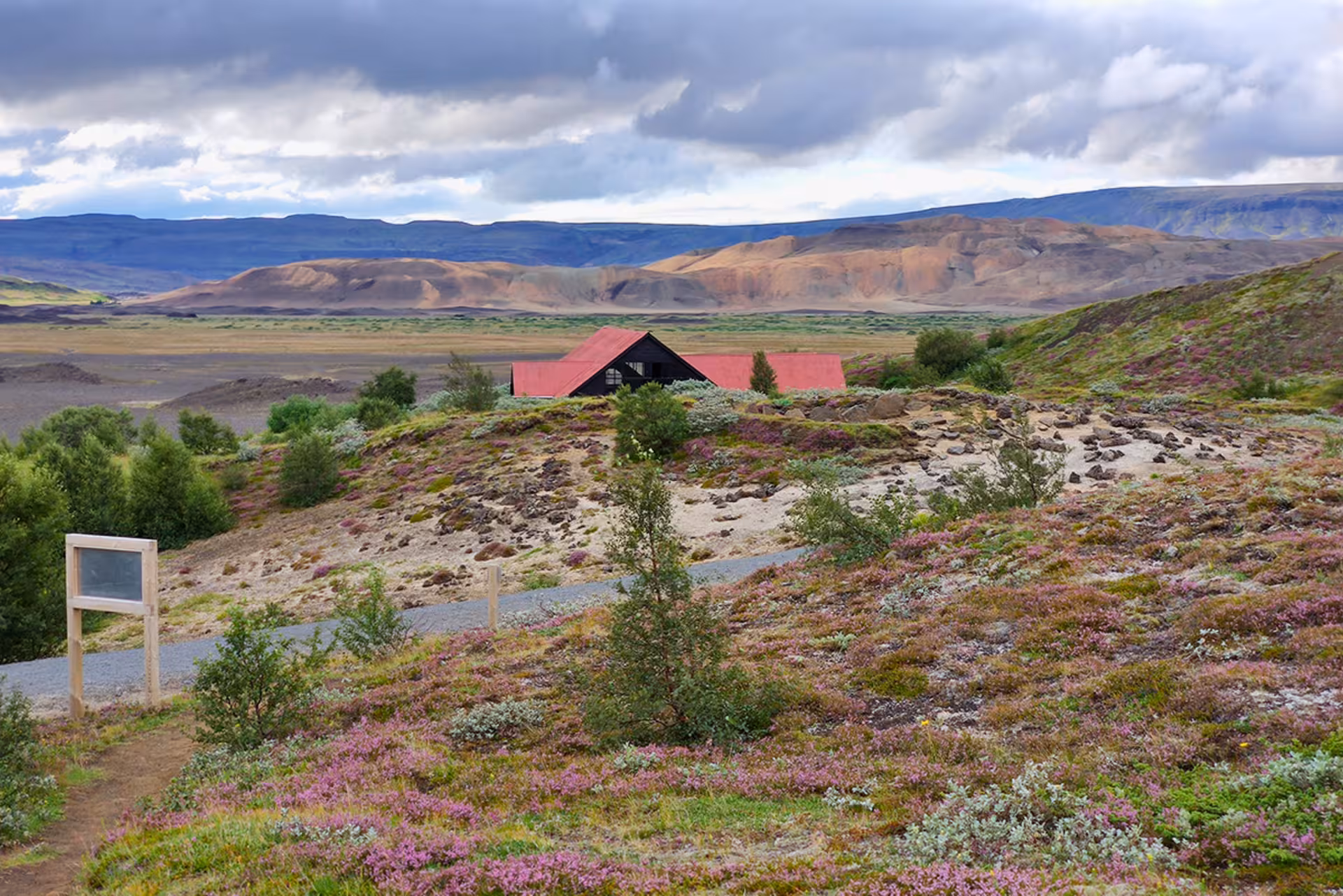 Red-roofed farmhouse amid heather hills in Þjórsárdalur Valley, Iceland, on a private scenic tour