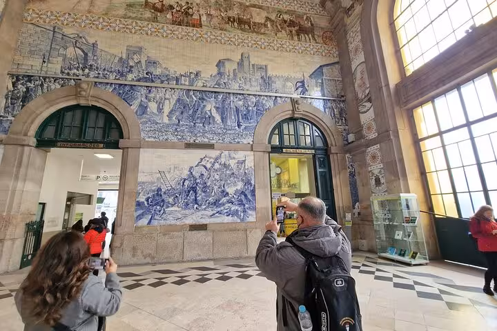 Visitors admiring São Bento Station blue azulejo murals on Three Shrines Pilgrimage tour Fátima Santiago Nazaré