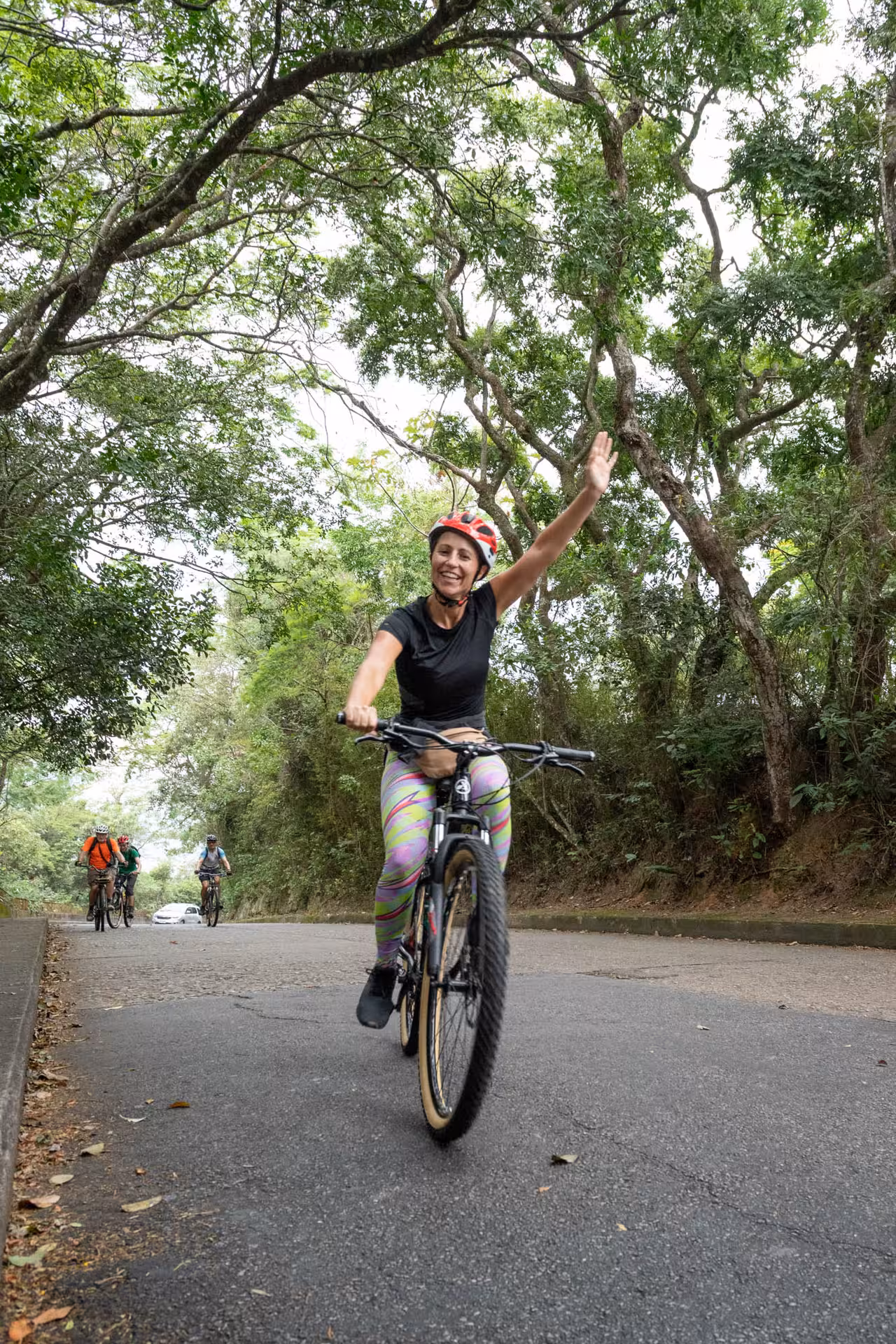 Smiling cyclist waves while riding in Tijuca Forest on Rio de Janeiro rainforest mountain bike tour