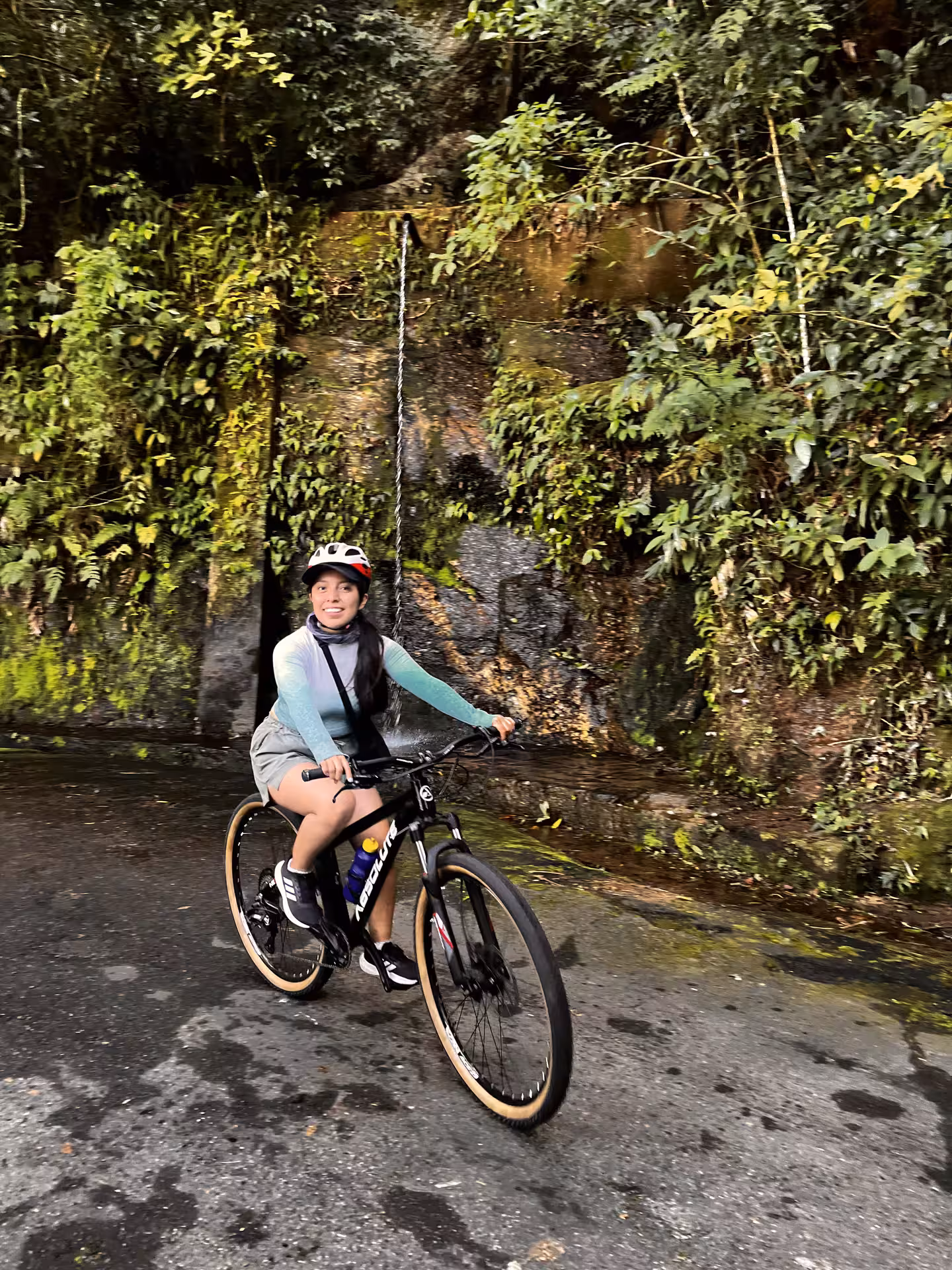 Mountain biker riding past a small waterfall on a lush Tijuca Forest trail in Rio de Janeiro rainforest