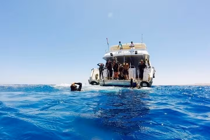 Boat anchored in the Red Sea for Tiran Island full-day cruise, with guests snorkeling from Sharm El Sheikh