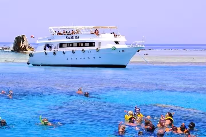 White yacht at Tiran Island with snorkelers in crystal-clear Red Sea on a full-day Sharm El Sheikh cruise