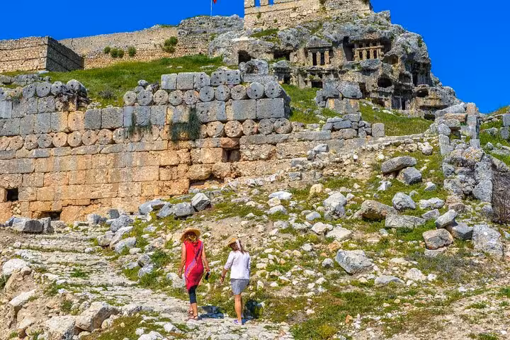 Visitors exploring ancient ruins of Tlos on a sunny day during a guided small group tour from Fethiye.