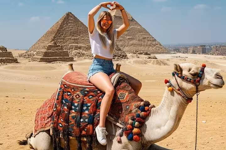 Tourist riding a camel at Giza Pyramids desert viewpoint, part of Grand Egyptian Museum, Sphinx and lunch day tour