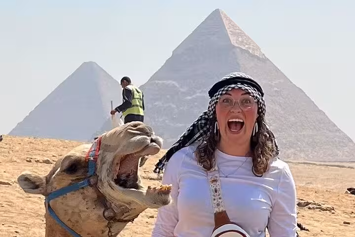 Smiling tourist with camel near the Pyramid of Khafre in Giza, Egypt.