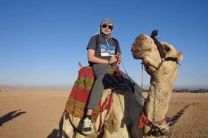 Tourist enjoying camel ride in Hurghada desert safari, seated on decorated camel under clear blue sky