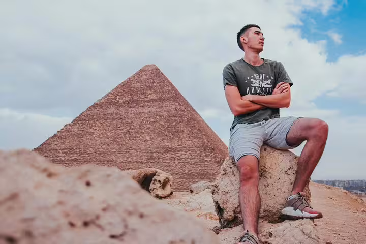Tourist posing near a Giza pyramid on Cairo sightseeing tour from Luxor by flight, 2-day package