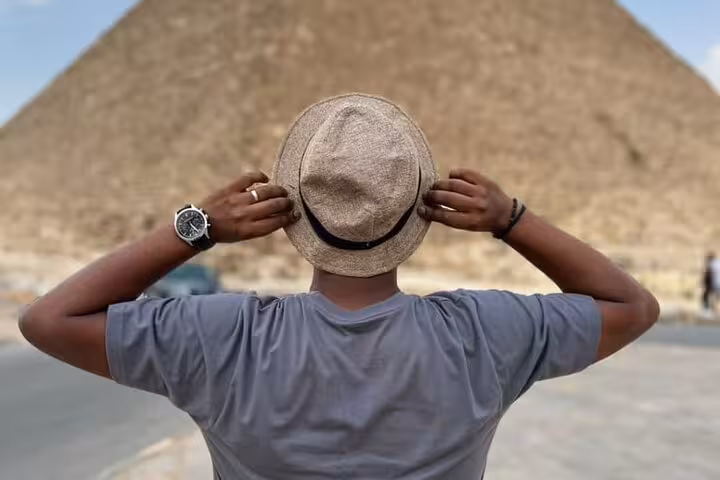 Tourist in hat facing the Giza Pyramid complex during a full-day guided Giza Pyramids tour in Cairo