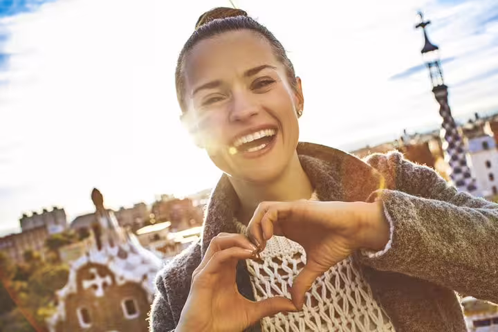 Smiling tourist makes a heart shape with hands, enjoying views of Gaudi architecture during a Sagrada Familia skip-the-line tour.