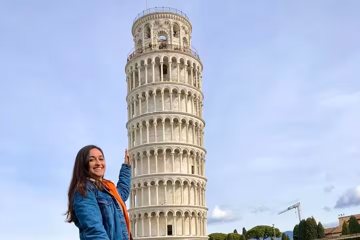 Smiling tourist poses playfully with Pisa's Leaning Tower during a private half-day trip from Florence.
