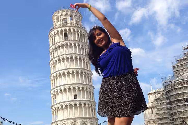 A tourist poses playfully with the Leaning Tower of Pisa, capturing a classic Italy travel moment.
