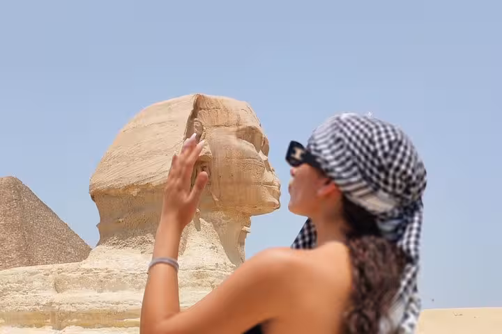 Tourist pretending to touch the nose of the Great Sphinx in Egypt.