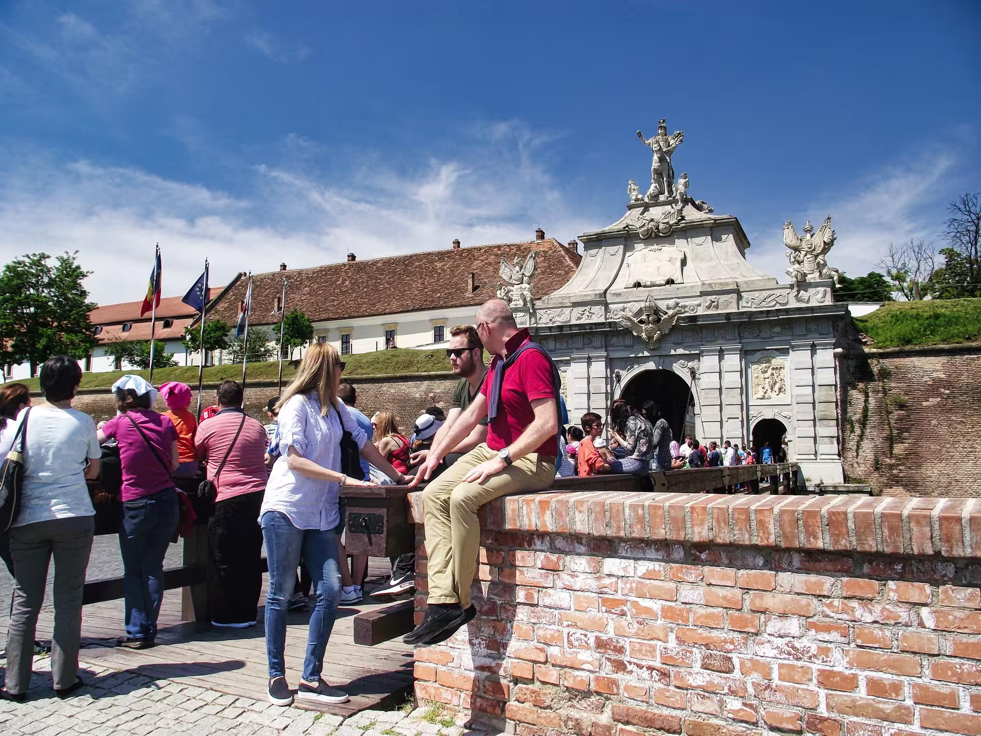Tourists exploring the ornate baroque gate of Alba Iulia fortress on a Best of Transylvania castles tour