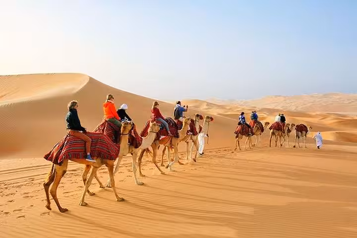 Tourists embark on a camel caravan journey through expansive desert landscapes, experiencing authentic desert culture.