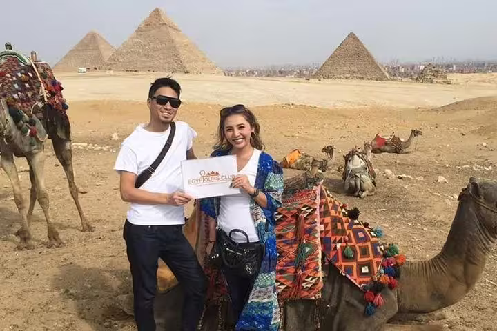 Tourists with camels at the Pyramids of Giza, Cairo day tour stop with desert panorama and pyramids