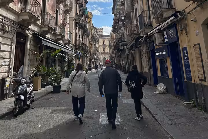 Tourists strolling through historic streets of Catania, capturing the charm of Sicilian architecture.