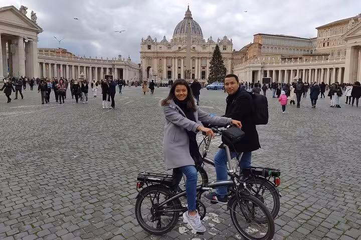 Tourists on e-bikes in St. Peter's Square, exploring Vatican City on the Rome Highlights by E-Bicycle tour.
