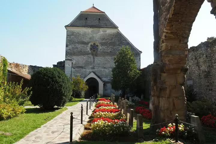 Medieval church with rose window surrounded by colorful flower gardens in Transylvania, Romania