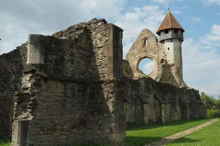 Medieval stone monastery ruins with circular window and watchtower in Transylvania, Romania