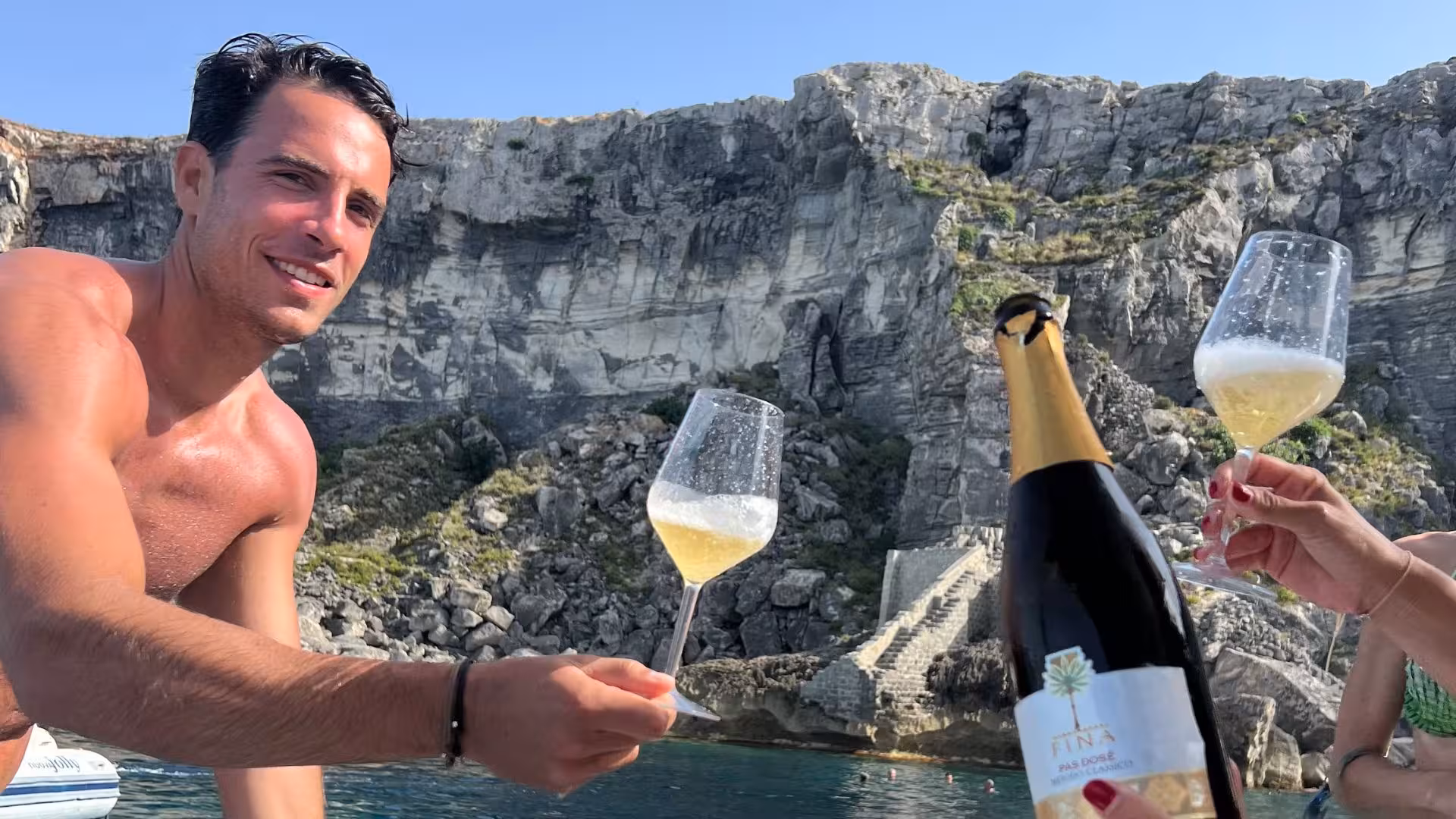 Toasting with sparkling wine on a dinghy tour near the stunning cliffs of Levanzo, capturing a moment of relaxation.