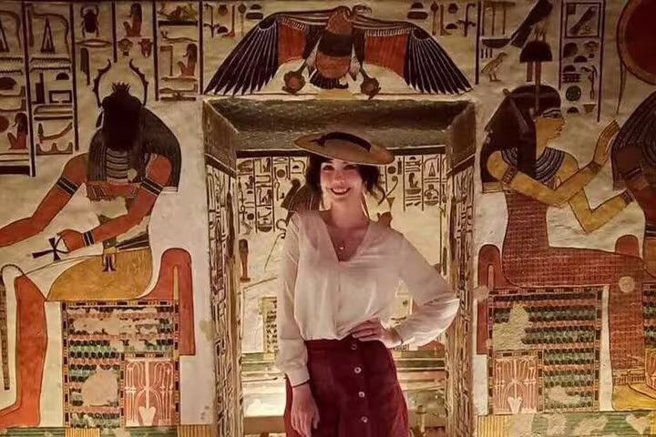 Traveler posing inside an ancient Egyptian tomb with vivid hieroglyphs in Luxor on a private tour from Safaga Port