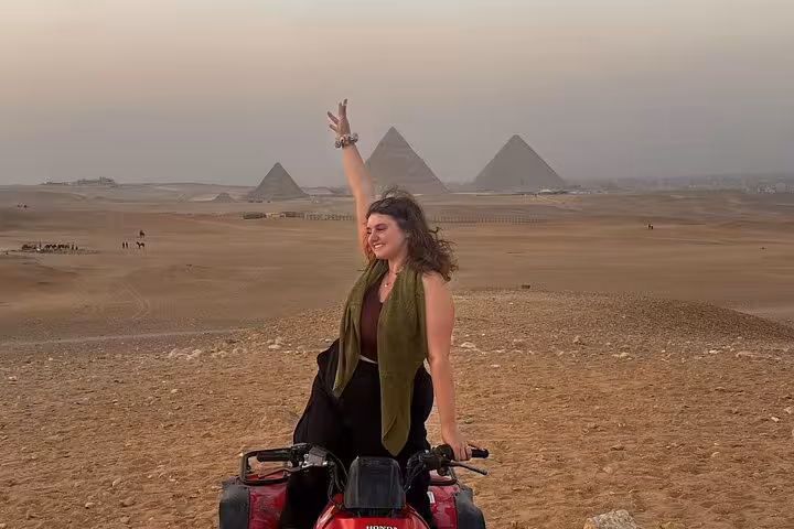 Traveler on an ATV ride in the Giza Desert with the Great Pyramids behind, Cairo adventure tour