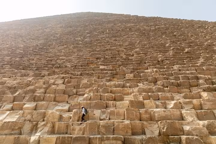 Traveler climbing the Great Pyramid of Giza stone blocks on Hurghada to Cairo day tour for first-time visitors