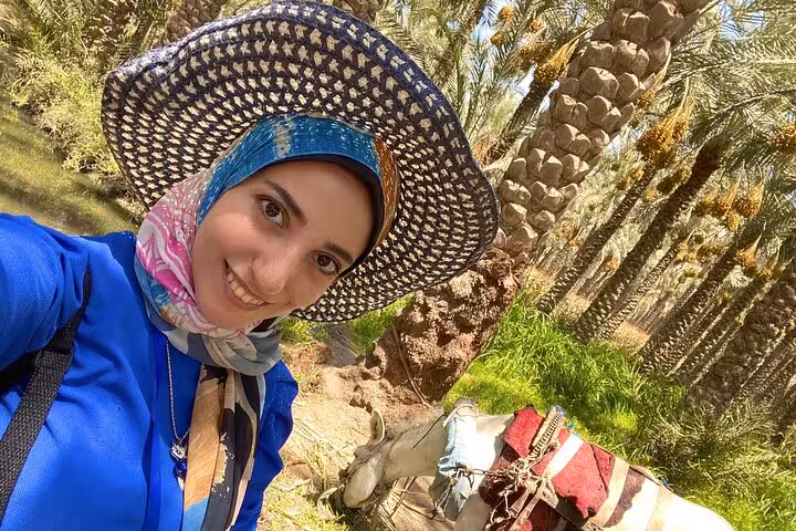 Traveler selfie with donkey in palm oasis near Memphis on Saqqara Dahshur day tour supporting stray animals