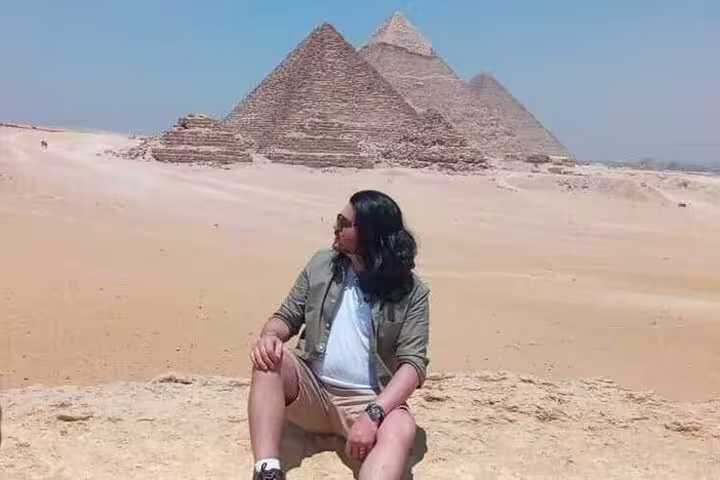 Traveler relaxing in front of the Giza Pyramids on a private day tour from Alexandria Port, Egypt