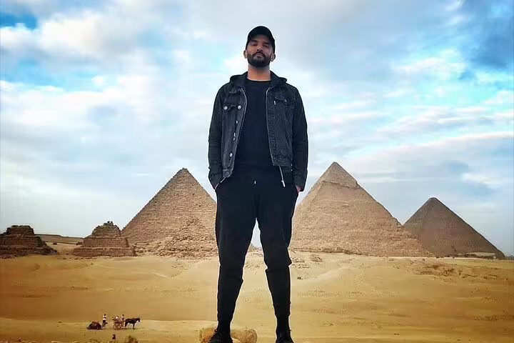 Traveler posing before the Giza Pyramids, Egypt, on a day tour with camel ride option and desert views