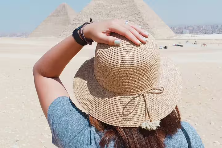 Traveler in sun hat facing the Giza Pyramids, photo moment on Pyramids, Memphis and Sakkara day trip