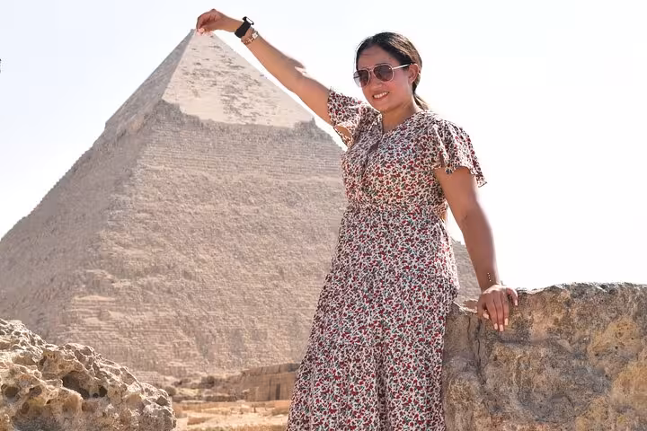Traveler posing by the Great Pyramid of Giza on a half-day private pyramids tour in Cairo, Egypt