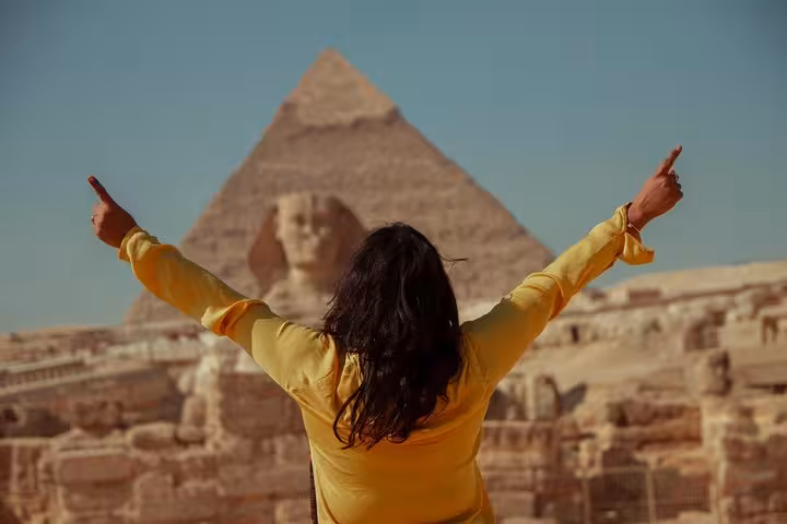 Traveler facing the Great Sphinx and Giza Pyramid on a private guided Cairo tour, arms raised