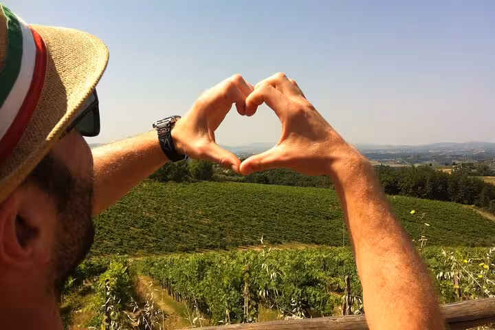 Traveler forming a heart shape with hands over scenic vineyards in Tuscany during Siena and San Gimignano tour.